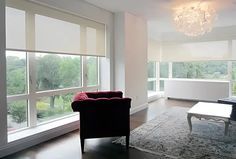 a living room filled with furniture next to large windows and a chandelier hanging from the ceiling