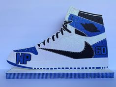 a pair of sneakers with blue and white designs on the side, sitting on top of a platform