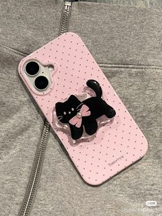 a pink phone case with a black cat brooch attached to it's side