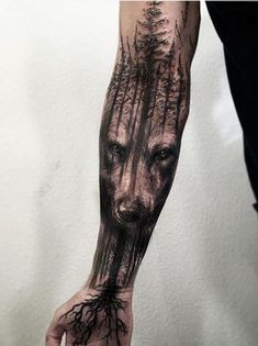 a man's arm with a wolf and tree tattoo on the left hand, which is covered in black ink