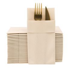 a stack of white napkins with gold forks on top of each one in front of the other