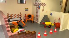 a play room with construction equipment on the floor and orange traffic cones in front of it