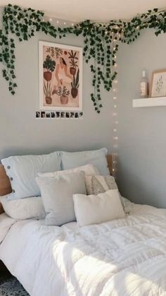 a white bed sitting under a window next to a wall with plants growing on it