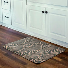 a kitchen with white cabinets and wood flooring on the wooden floor is an area rug that looks like waves