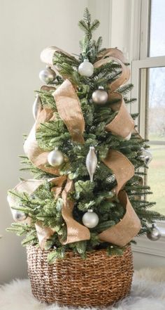 a small christmas tree in a wicker basket with burlocks and ornaments on it