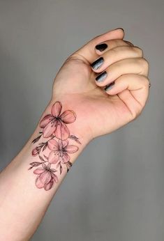 a woman's arm with pink flowers on it and black dots around the wrist