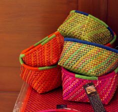 colorful baskets sitting on top of a table next to a bowl and spoon with an orange tag