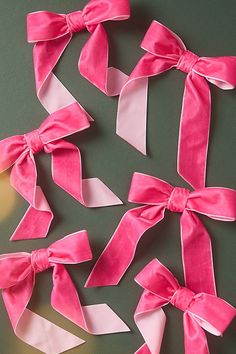 pink and white ribbons tied together on a green surface with one being cut into smaller pieces