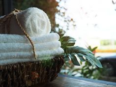 a basket filled with white towels sitting on top of a wooden table