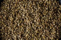 a pan filled with green lentils on top of a wooden table next to a knife