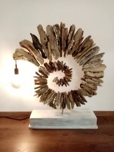 a sculpture made out of driftwood sitting on top of a wooden table next to a lamp