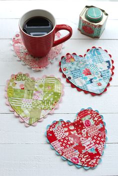 four heart shaped coasters sitting on top of a table next to a cup of coffee