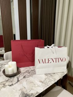 a table topped with two bags and candles next to each other on top of a marble counter