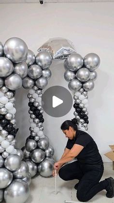 a man kneeling down next to a giant balloon arch