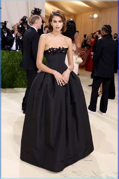 a woman in a black dress standing on a white carpet