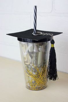 a graduation cap on top of a cup filled with pencils and paperclip