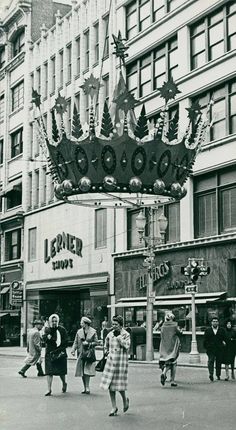 an old black and white photo of people walking in front of a theater marquee