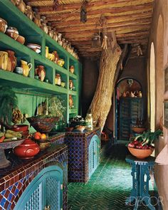 the kitchen is decorated in green and blue with lots of dishes on the shelves above