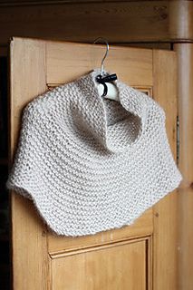 a white knitted shawl hanging on a wooden door with a black bow tie