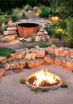 an outdoor fire pit surrounded by rocks and grass