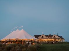 a large white tent set up in front of a house with lights on the roof