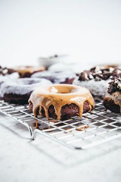 chocolate donuts with frosting and sprinkles sitting on a cooling rack