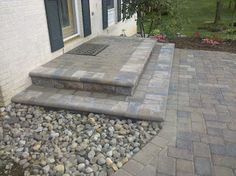 a brick patio with steps leading up to the front door