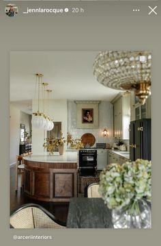 a kitchen with an island and chandelier hanging from it's ceiling in front of a dining room table