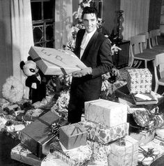 a man in a suit holding a large box full of presents on top of a table