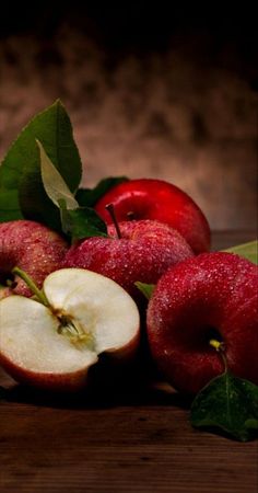 some apples and leaves on a wooden table