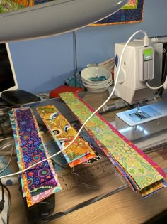 the sewing machine is hooked up to some colorful fabrics on the table next to it