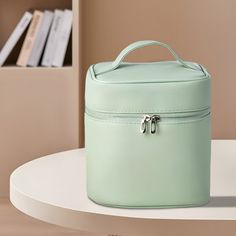 a mint green lunch box sitting on top of a table next to a book shelf