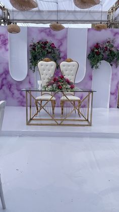 two white chairs sitting on top of a table in front of purple and white walls