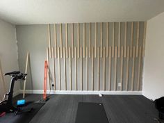 an empty room with some exercise equipment in front of a wall that has vertical slats on it