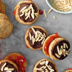 several cookies with white chocolate and almonds on top, next to a bowl of macaroni and cheese