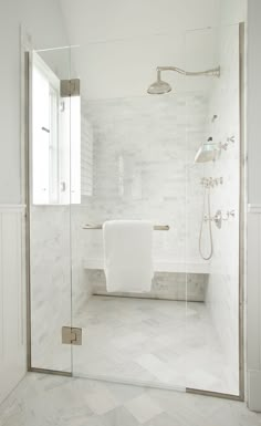 a white bathroom with marble flooring and glass shower door, along with a tub