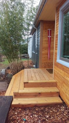 a wooden deck in front of a house with steps leading up to the back door