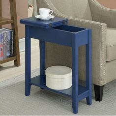 a blue end table with a cup on it and a book shelf in the corner