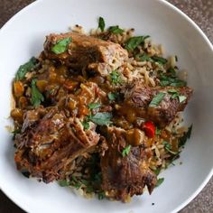 a white bowl filled with meat and rice on top of a wooden table next to a fork