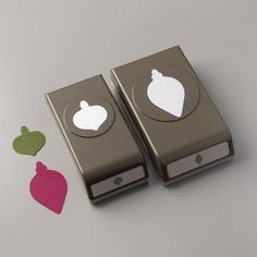 two silver electronic devices sitting next to each other on top of a white table with cut out hearts