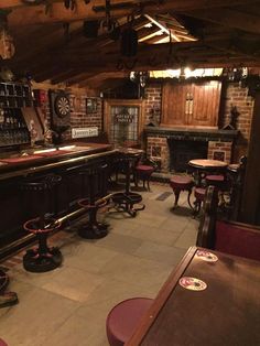 the interior of a bar with several stools and tables in front of it, along with an open fire place