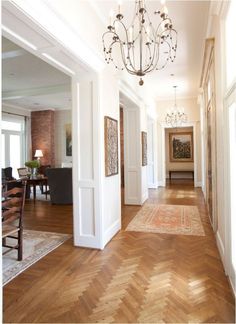 an image of a hallway with wood floors and chandelier