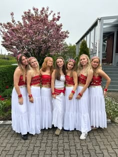 a group of young women standing next to each other in white skirts and red tops