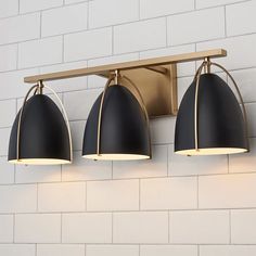 three lights are hanging on the wall next to a white brick wall in a bathroom