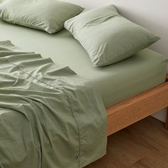 a bed with green sheets and pillows on it