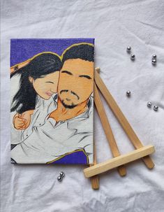 an image of a man and woman holding each other on a piece of fabric next to wooden pegs