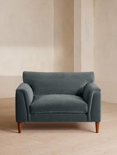 a blue couch sitting on top of a hard wood floor next to a white wall