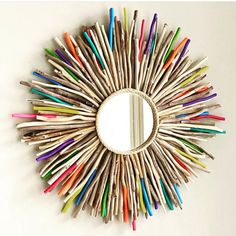 a circular mirror made out of sticks and colored pencils on the inside of it