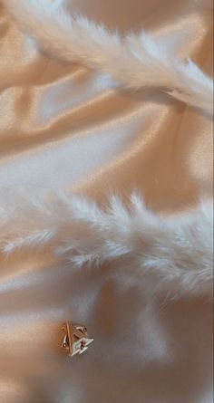 a close up view of a white feathery fabric with a gold brooch on it