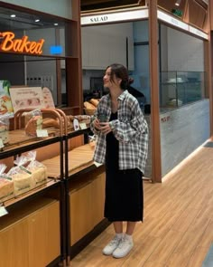 a woman standing in front of a bakery counter looking up at the food on display